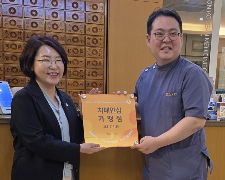 화성특례시가 22일 신규 치매안심가맹점으로 지정된 보건한의원에 현판을 전달하고 있다